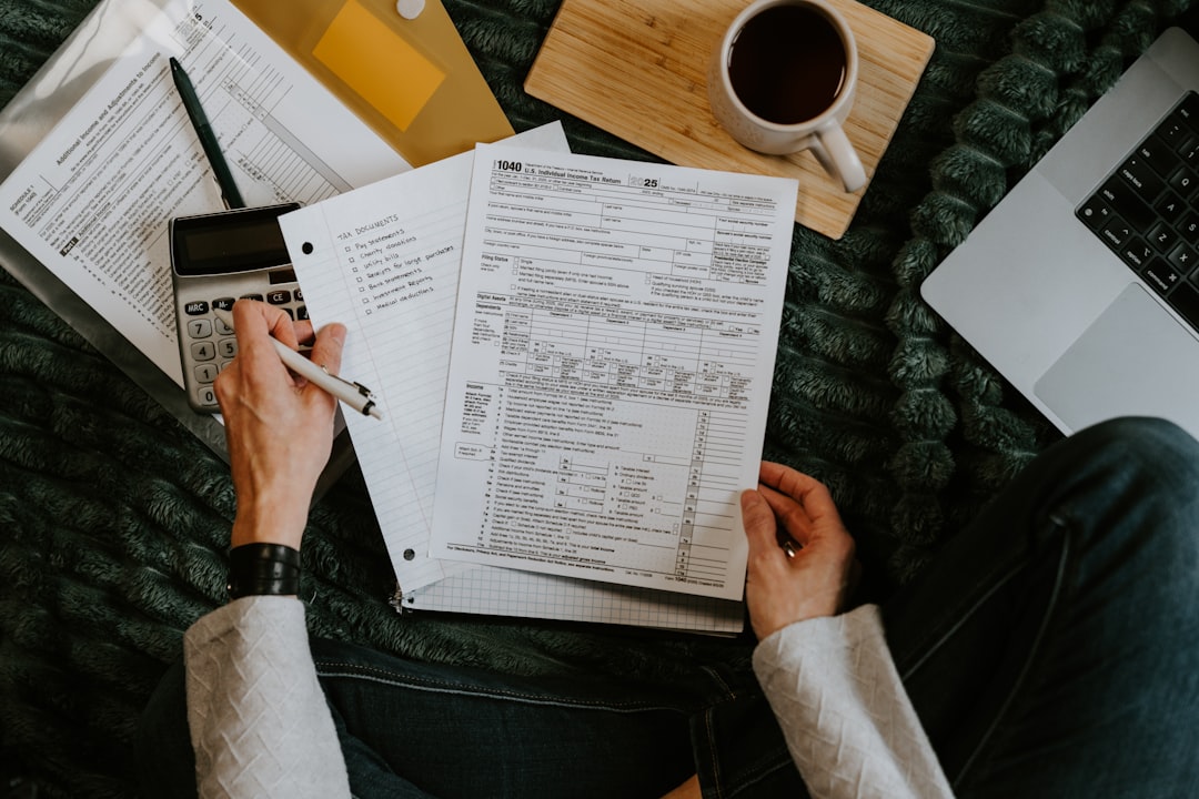 person-reviewing-documents-with-calculator-and-laptop-tlqtcdzltps